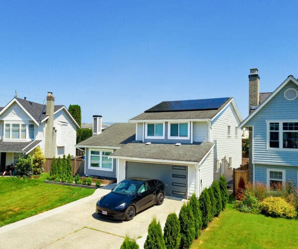 solar panels on home with tesla car charging in driveway
